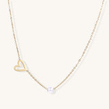 Dainty 14K gold-plated necklace with open heart pendant and white pearl bead on neutral background