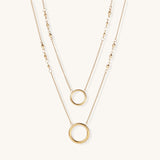 Gold-plated layered necklace set with two circular pendants featuring white centers on delicate chains.