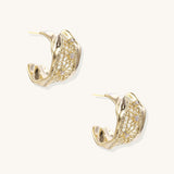 Close-up of gold-plated brass hoop earrings with geometric lattice pattern and sparkling zirconia stones