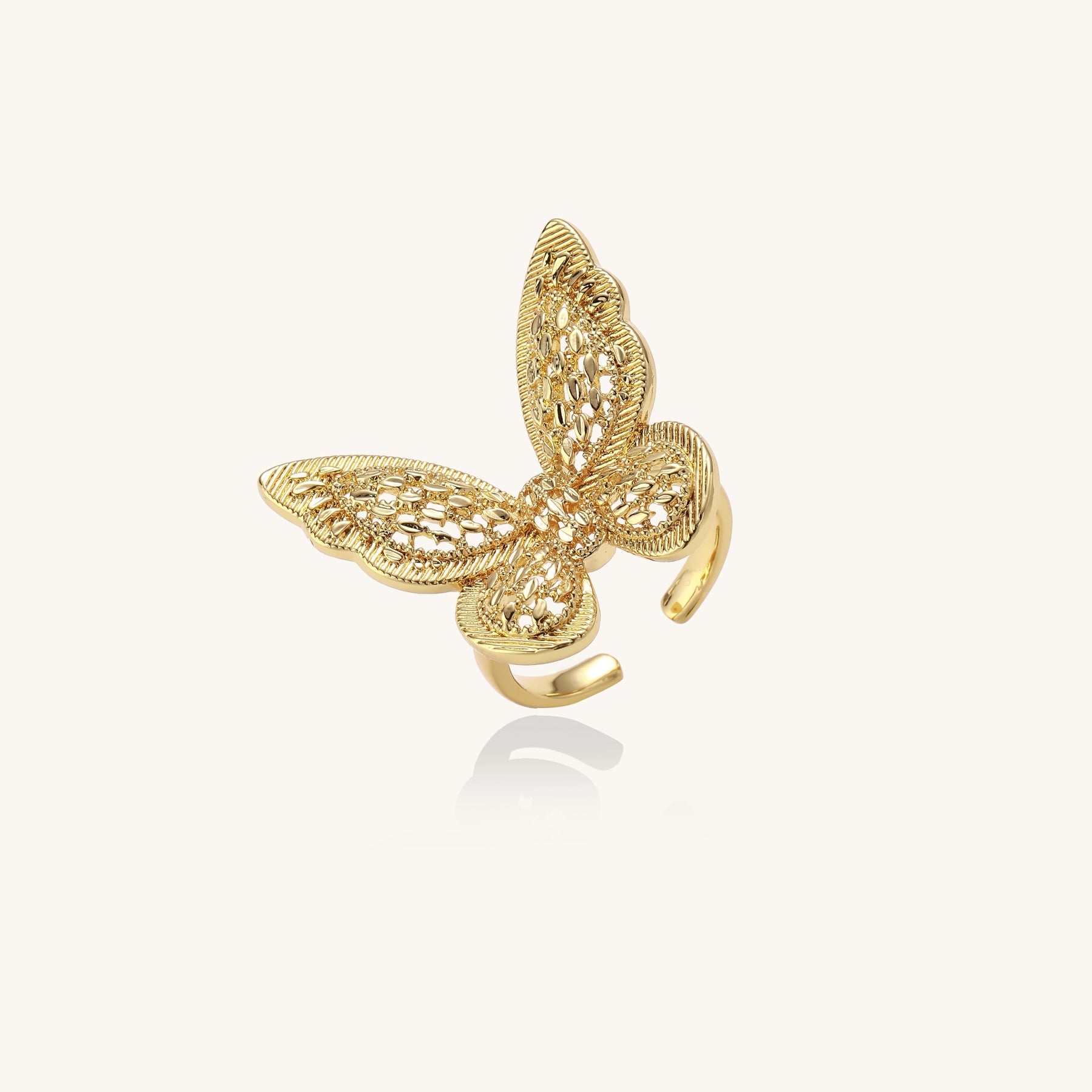 Adjustable gold-plated brass butterfly ring with intricate filigree cutout patterns and cubic zirconia accents on white background.