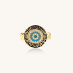 Gold-plated brass ring with Greek key border, evil eye center, and turquoise cubic zirconia stones in chunky chain band style.