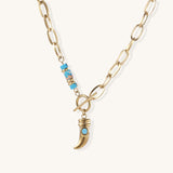 Gold-plated chain necklace with toggle clasp, turquoise beads, and curved horn pendant with inset turquoise stone on light background.
