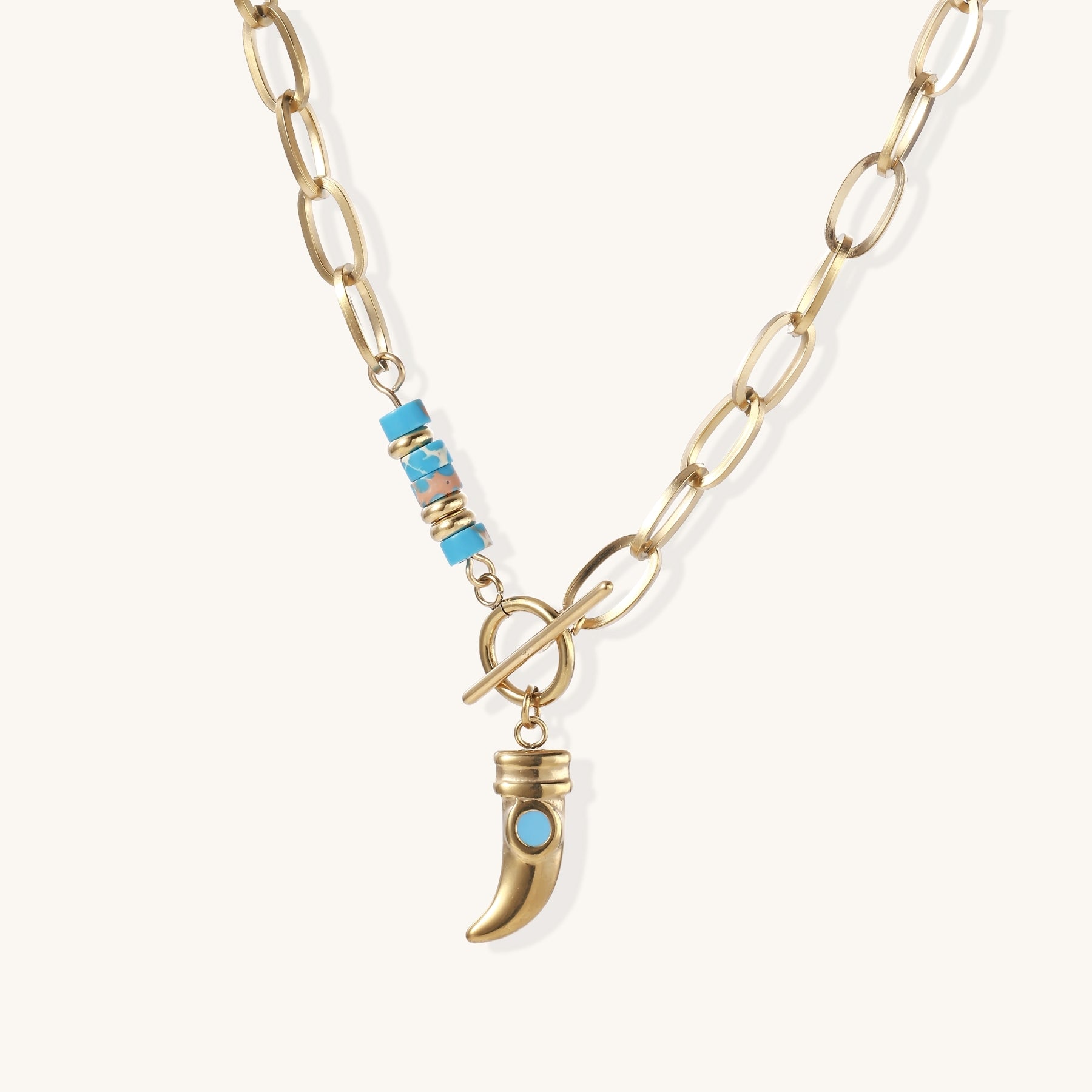 Gold-plated chain necklace with toggle clasp, turquoise beads, and curved horn pendant with inset turquoise stone on light background.