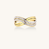 Gold-plated stainless steel ring with crossed infinity bands adorned with sparkling rhinestones against cream background.