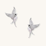 Pair of gold-plated hummingbird earrings with crystal pavé wings and black stone eyes on neutral background.