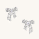 Gold and silver bow-shaped earrings with intricate lattice pattern and clear zirconia stones on neutral background.