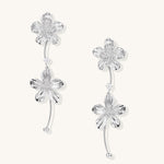 Gold-plated floral dangle earrings with zirconia crystal centers and curved stems on white background.