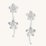 Gold-plated floral dangle earrings with zirconia crystal centers and curved stems on white background.