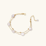 Double-strand gold bracelet with irregular baroque pearls and smooth freshwater pearls on cream background.