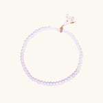 Double-wrap lavender beaded bracelet with rose quartz, pearls, gold vermeil charm and pink tassel on white background.