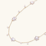 Gold vermeil chain with iridescent star-shaped baroque pearls and small round freshwater pearl drops on cream background.
