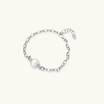 Rhodium-plated silver chain bracelet with single white freshwater pearl and heart charm clasp on cream background