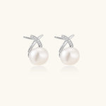Rhodium-plated silver stud earrings with sparkling X design above lustrous round freshwater pearls on white background.