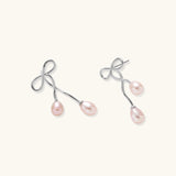 Rhodium-plated silver earrings with organic vine curves and two peachy freshwater pearls on cream background