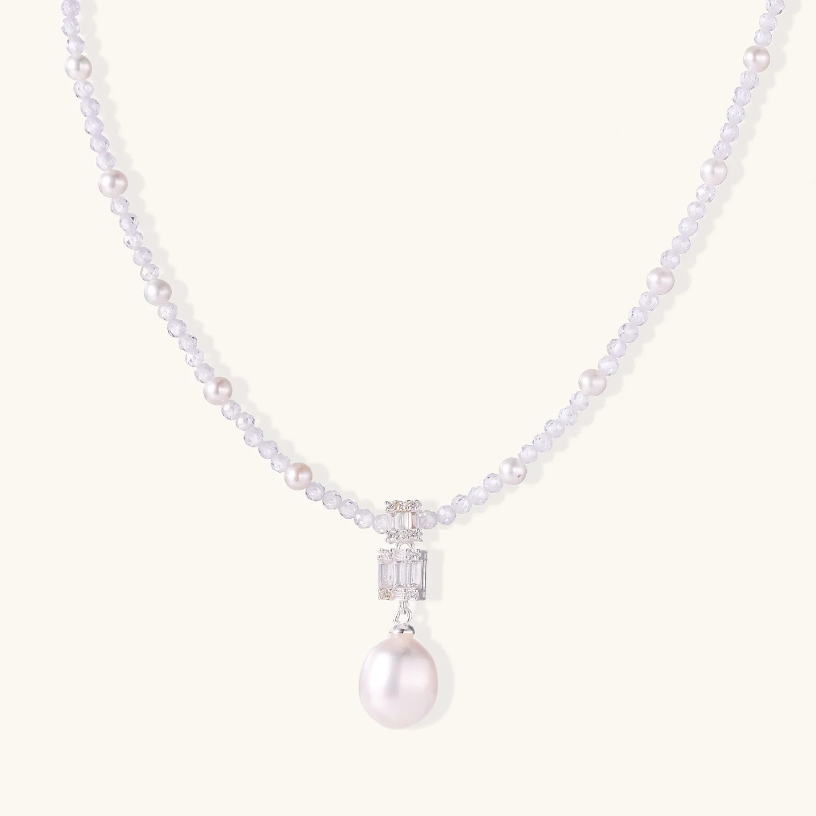 Dainty necklace with lavender crystal beads, freshwater pearls, geometric pendant, and large pearl drop on white background.