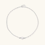 Dainty rhodium-plated silver chain necklace with centered 10mm freshwater pearl and crystal accents on cream background