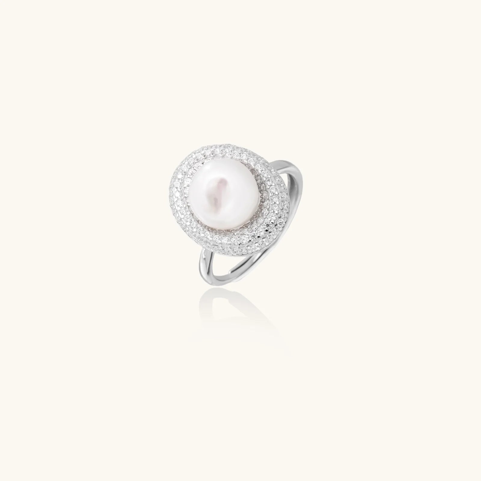 Silver ring with lustrous white pearl center surrounded by sparkling crystal halo on light background.