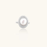 Silver ring with lustrous white pearl center surrounded by sparkling crystal halo on light background.