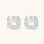 Pair of geometric sterling silver earrings with frosted square frames and glossy rounded studs on white background