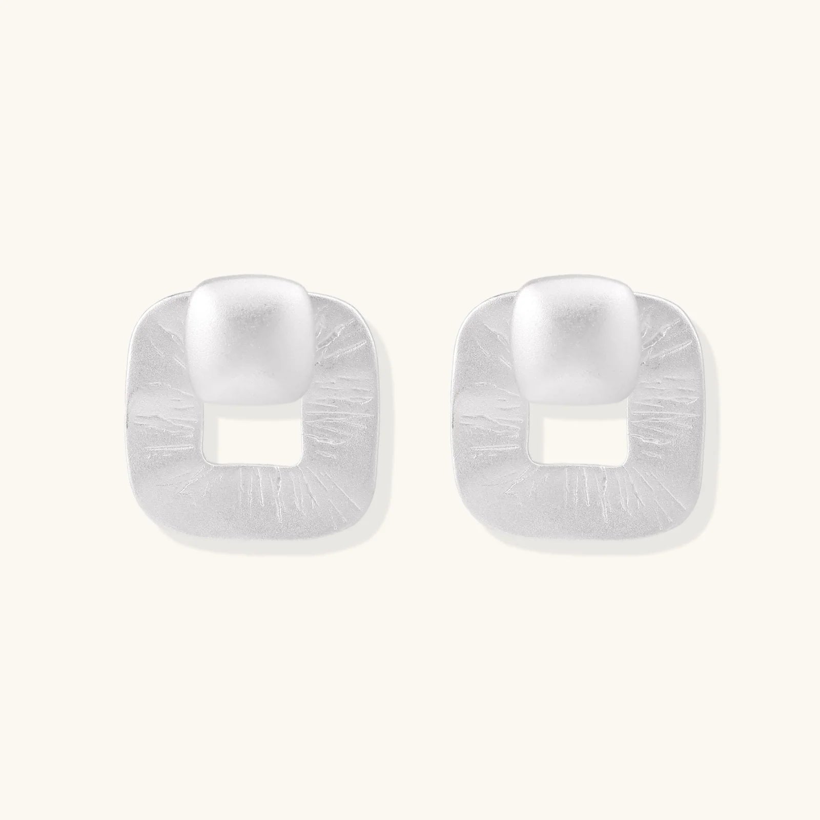 Pair of geometric sterling silver earrings with frosted square frames and glossy rounded studs on white background