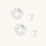 Pair of geometric sterling silver earrings with frosted square frames and glossy rounded studs on white background
