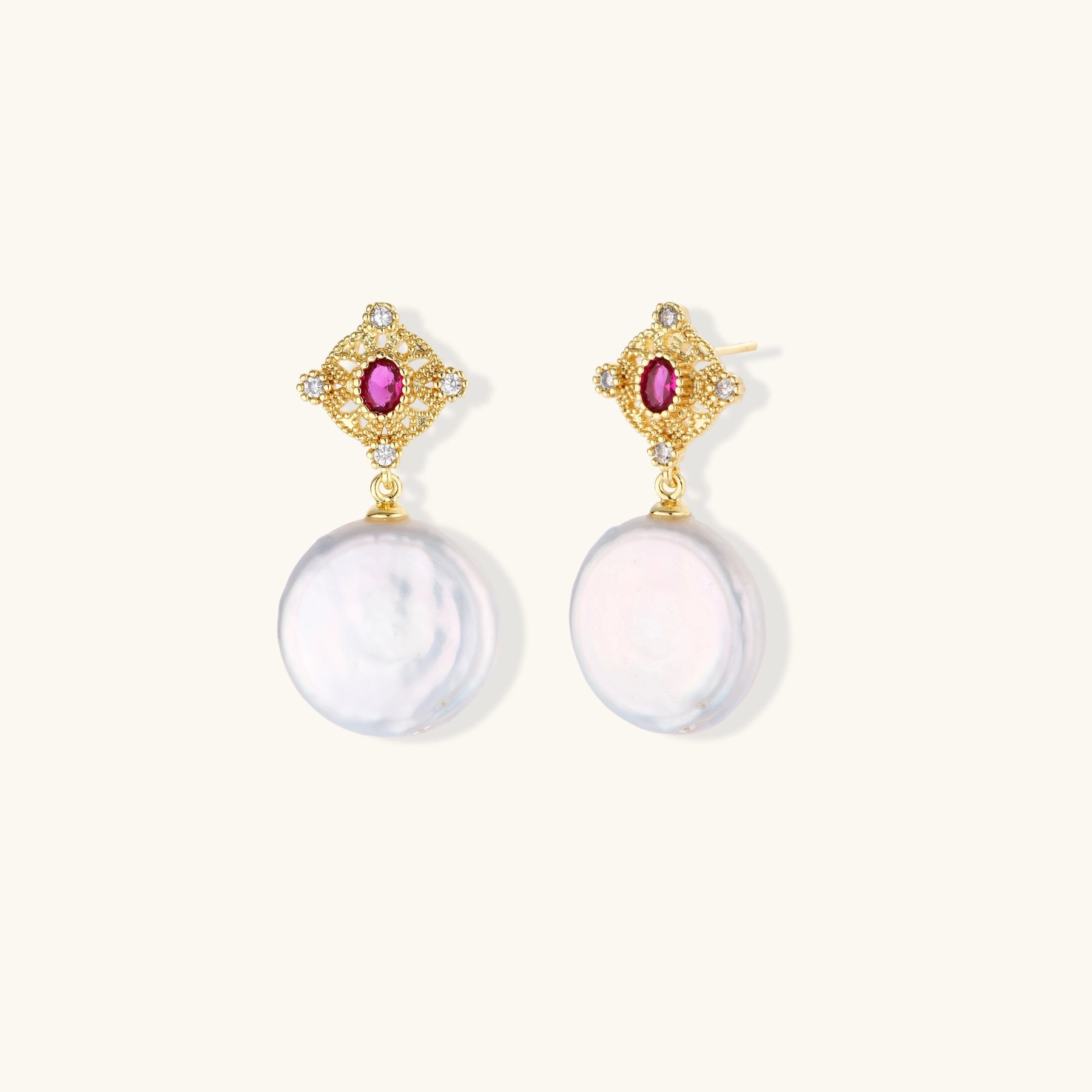 Gold baroque pearl earrings with pink gemstone studs and ornate detailing on cream background.