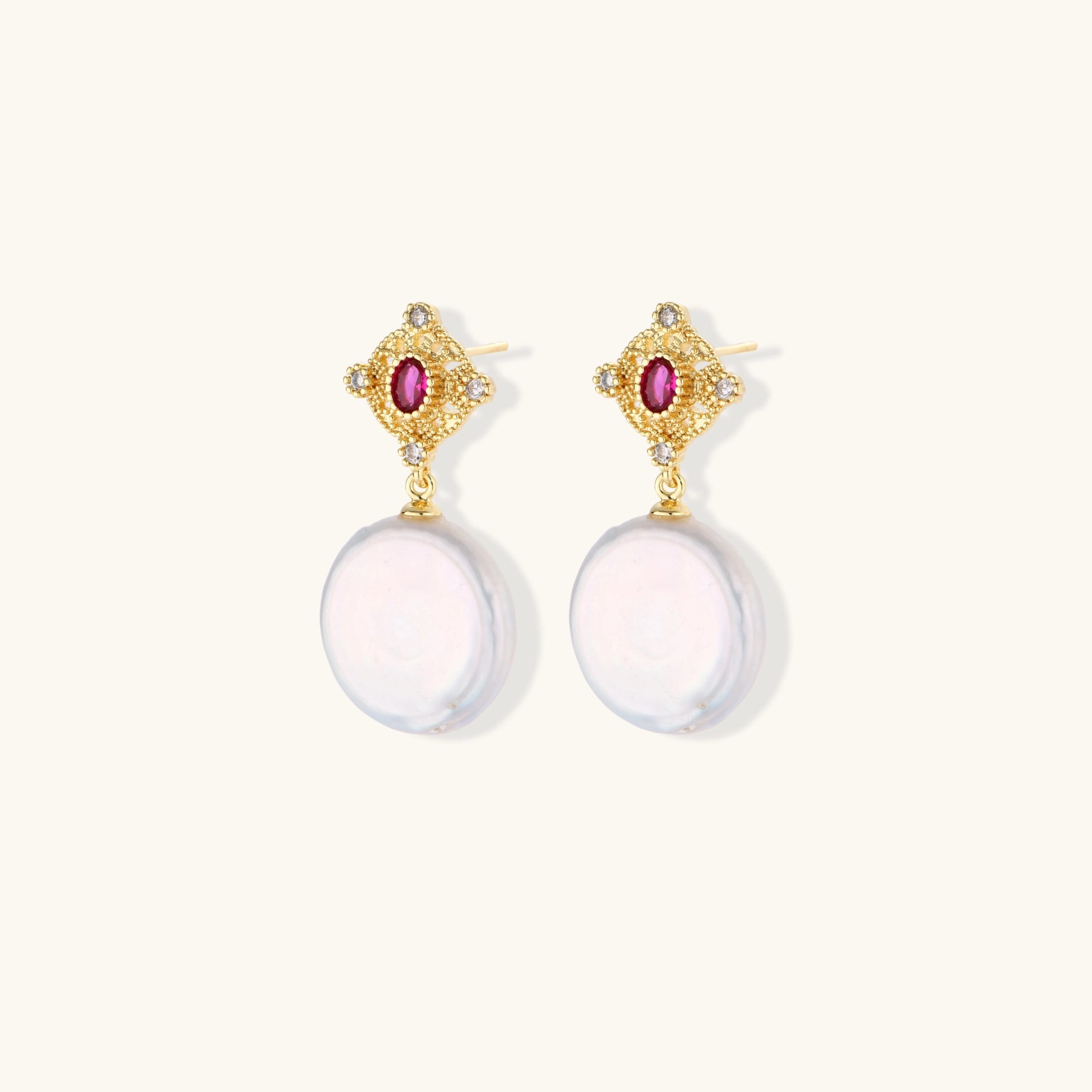 Gold baroque pearl earrings with pink gemstone studs and ornate detailing on cream background.
