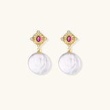 Gold baroque pearl earrings with pink gemstone studs and ornate detailing on cream background.