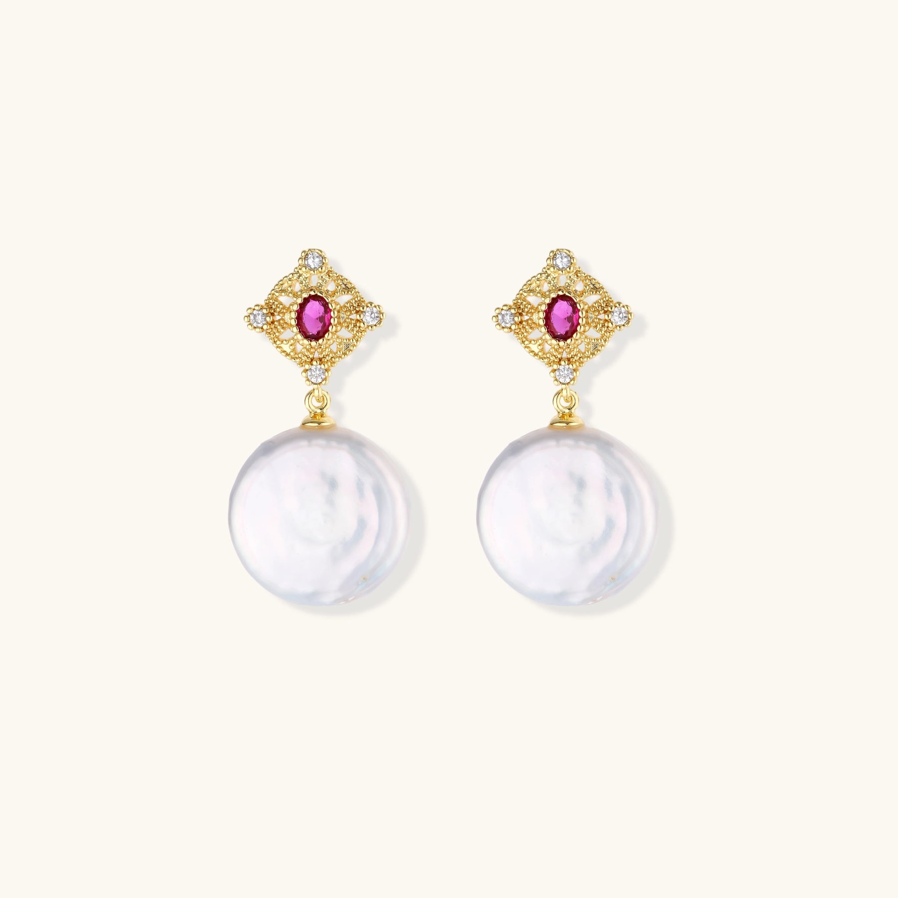 Gold baroque pearl earrings with pink gemstone studs and ornate detailing on cream background.
