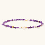 Beaded necklace with purple amethyst chips, freshwater pearls, and gold accents on white background.