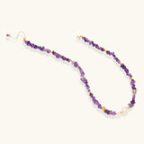 Beaded necklace with purple amethyst chips, freshwater pearls, and gold accents on white background.