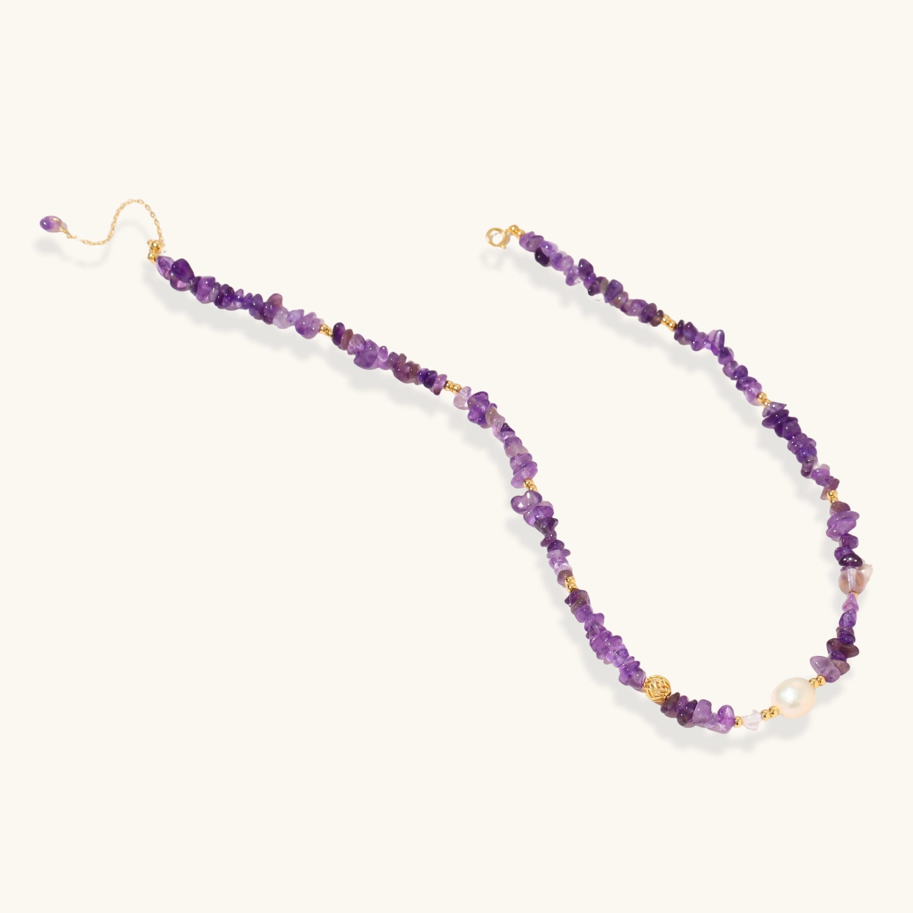 Beaded necklace with purple amethyst chips, freshwater pearls, and gold accents on white background.