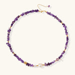 Beaded necklace with purple amethyst chips, freshwater pearls, and gold accents on white background.