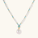 Beaded necklace with baroque pearls, turquoise stones, and gold accents featuring a large pearl pendant on white background.