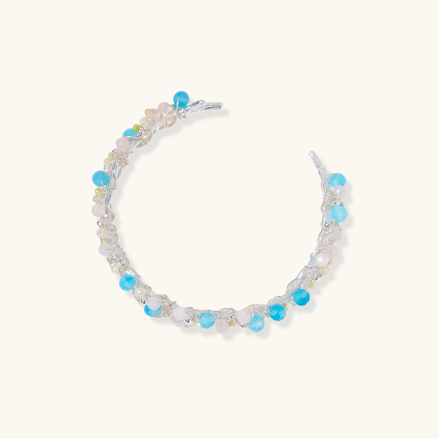Delicate wire-wrapped bracelet featuring turquoise, rose quartz, freshwater pearls, and zircon on a white background.