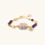 Gold-plated bracelet with baroque pearl centerpiece, amethyst beads, and crystal star charm on white background.