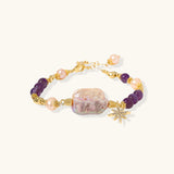 Gold-plated bracelet with baroque pearl centerpiece, amethyst beads, and crystal star charm on white background.