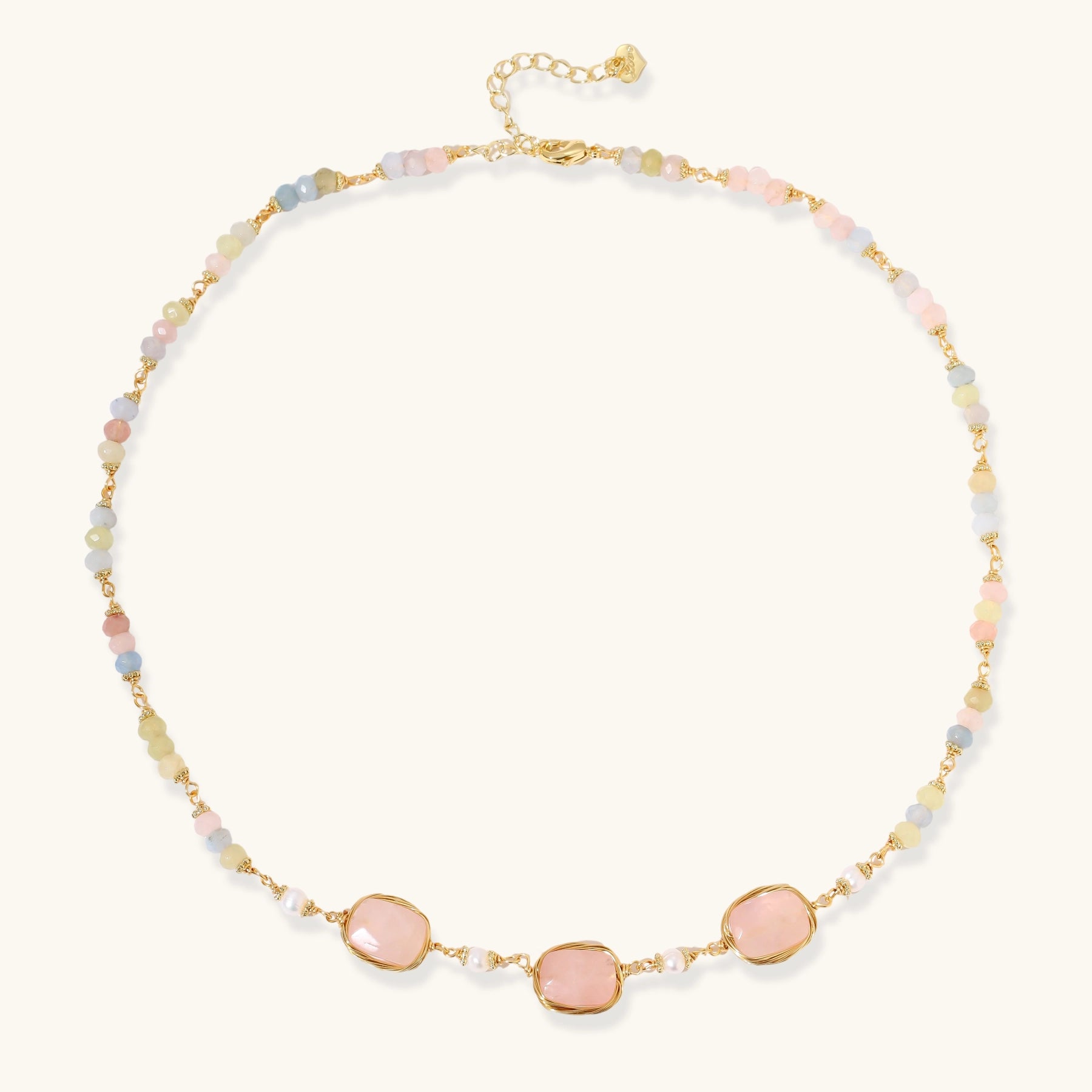 Gold necklace with three rose quartz stones, multicolor pastel beads, and pearl accents on white background.