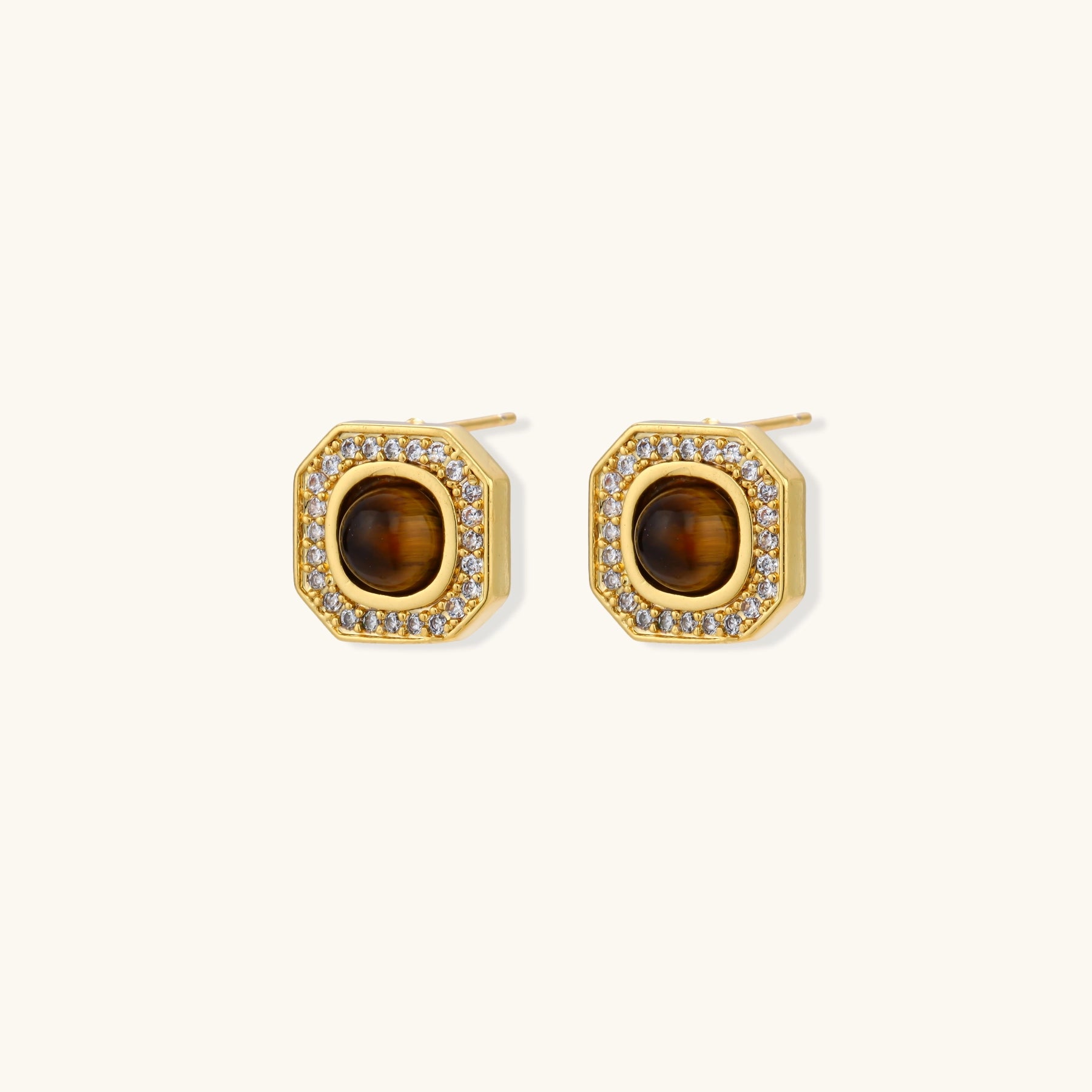 Gold-plated octagonal stud earrings with brown tiger's eye centers and cubic zirconia border on cream background.
