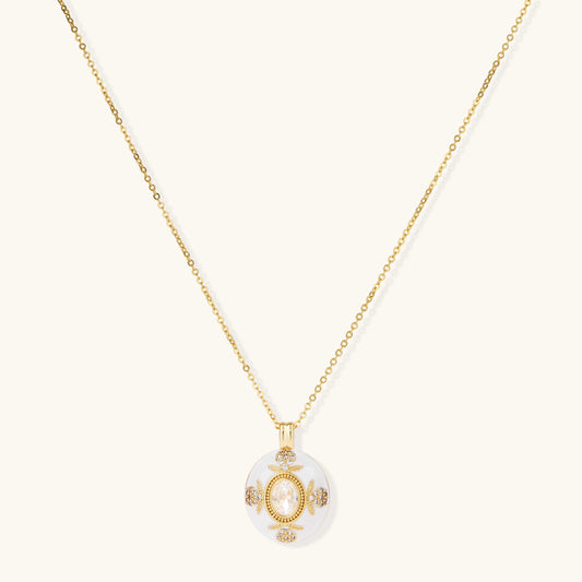 Gold-plated necklace with circular white enamel pendant featuring central zirconia stone and ornate decorative details