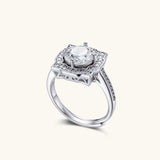 Sterling silver ring with round moissanite center stone in ornate scalloped halo setting on white background.