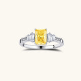 Sterling silver ring with emerald-cut yellow moissanite center stone and clear baguette side stones in elegant setting
