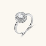 Sterling silver ring with oval moissanite center stone surrounded by double halo of sparkling stones on neutral background.