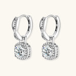 Sterling silver twisted hoop earrings with round moissanite stones in halo settings against neutral background.