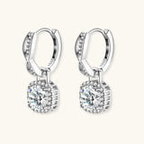 Sterling silver twisted hoop earrings with round moissanite stones in halo settings against neutral background.