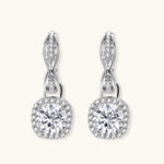 Sterling silver twisted hoop earrings with round moissanite stones in halo settings against neutral background.