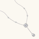 Sterling silver necklace with cushion-cut moissanite halo pendant and teardrop drop on white background