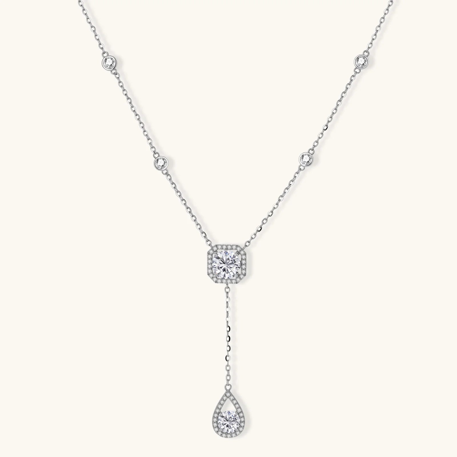Sterling silver necklace with cushion-cut moissanite halo pendant and teardrop drop on white background