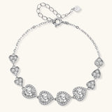 Sterling silver bracelet with graduated heart-shaped links and sparkling moissanite stones in VVS1 clarity on white background.