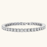 Sterling silver tennis bracelet with continuous row of brilliant moissanite stones and secure clasp closure on cream background.